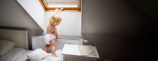 Toddler standing up on mattress for Sleepology blog