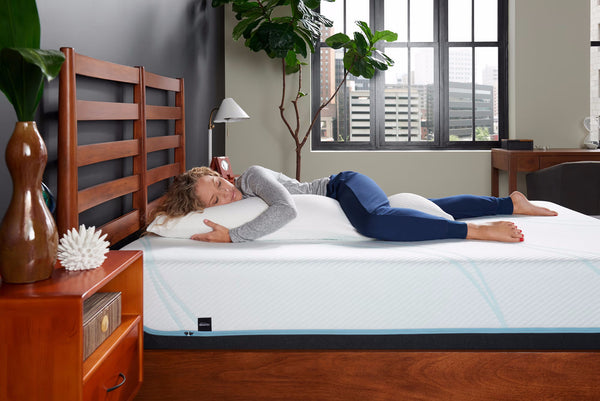 A woman resting comfortably with a Tempur-Pedic Body Pillow, showcasing ergonomic support and full-body alignment for side sleepers, ideal for a relaxing sleep experience, available at Sleepology Mattress Shop.